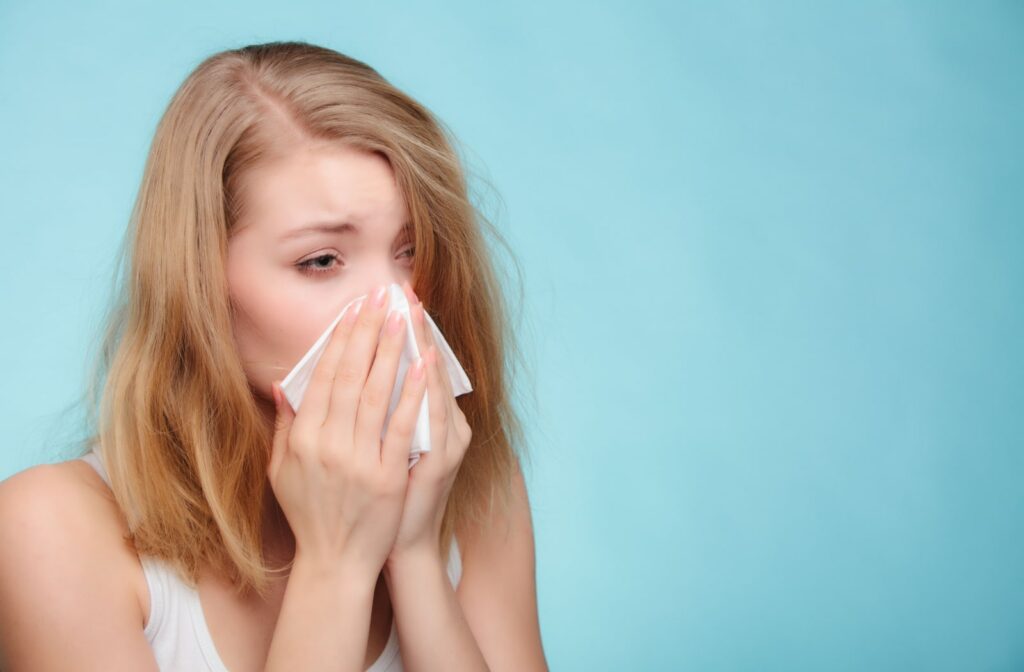 A young woman with allergies is suffering from drowsy eyes and a runny nose