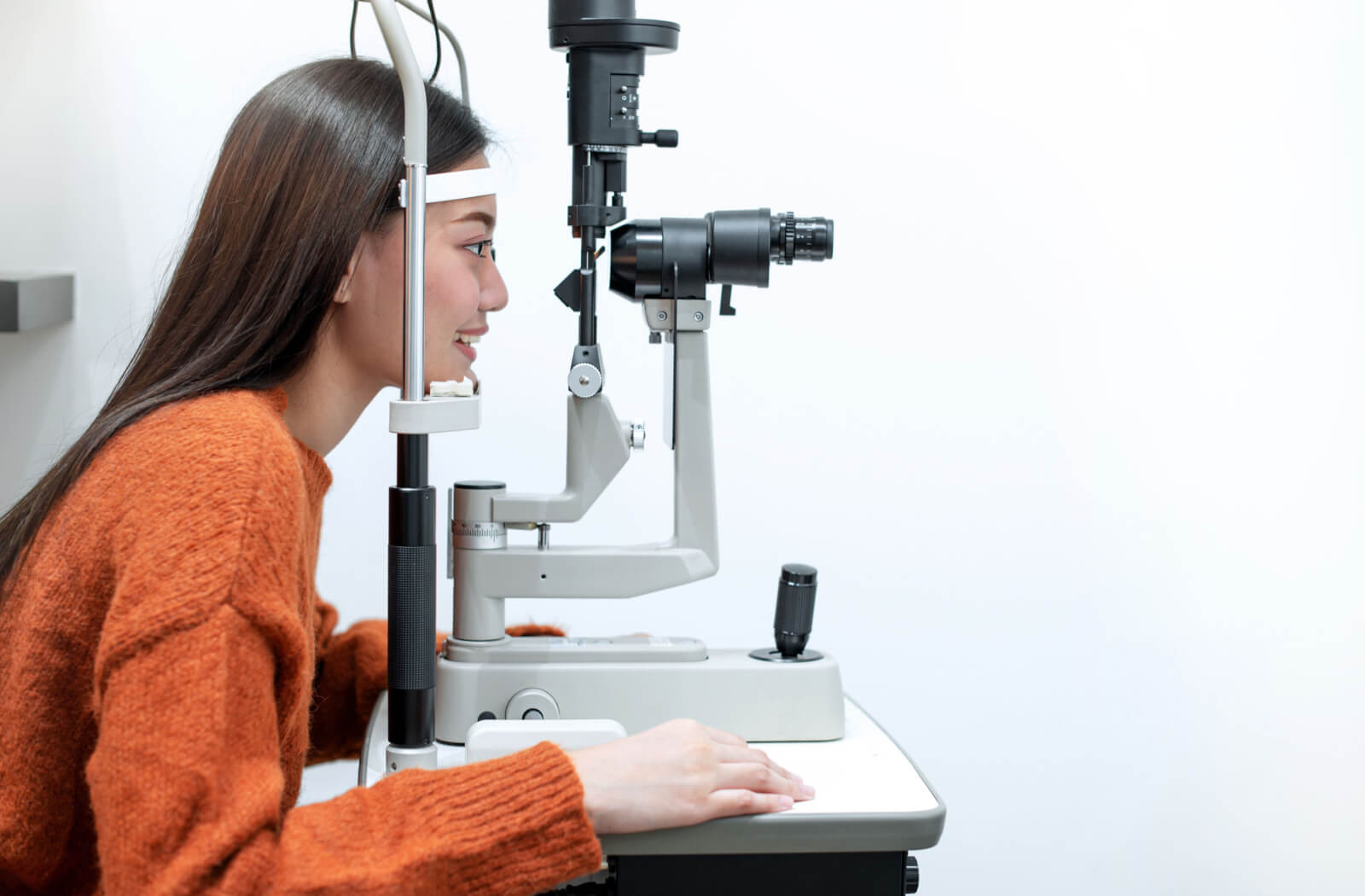 A woman sitting in an optometrist's office looking into a machine that tests her vision.