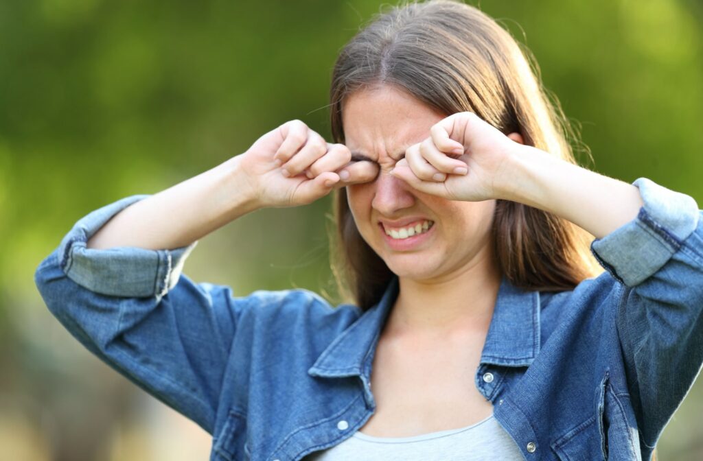 A woman rubbing her eyes with both hands.