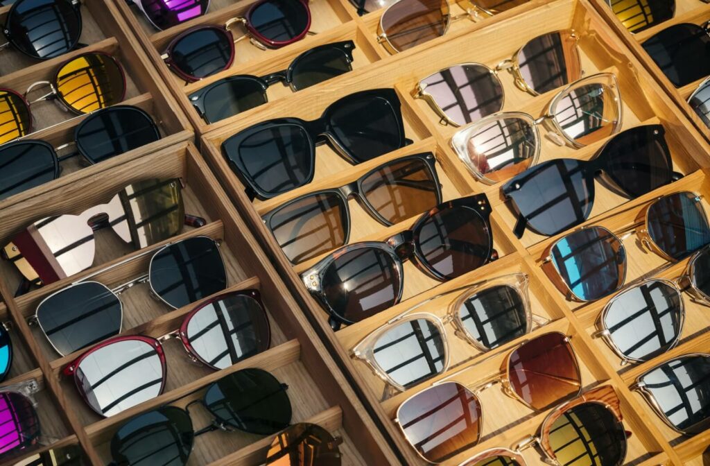 A variety of sunglasses in wooden display cases.