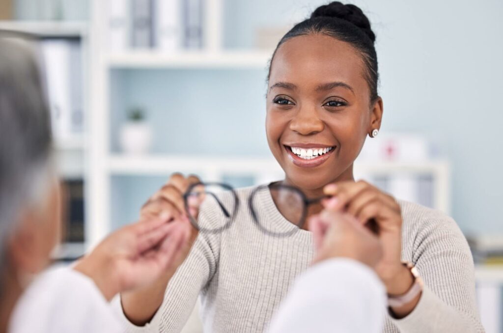 A patient excitedly takes their new prescription glasses from the optometrist.