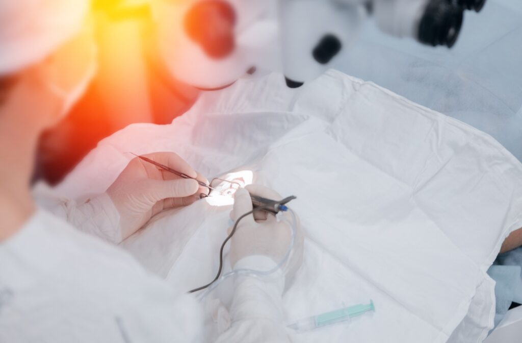 A surgeon stands above a covered patient with medical tools poised to assist with laser eye surgery