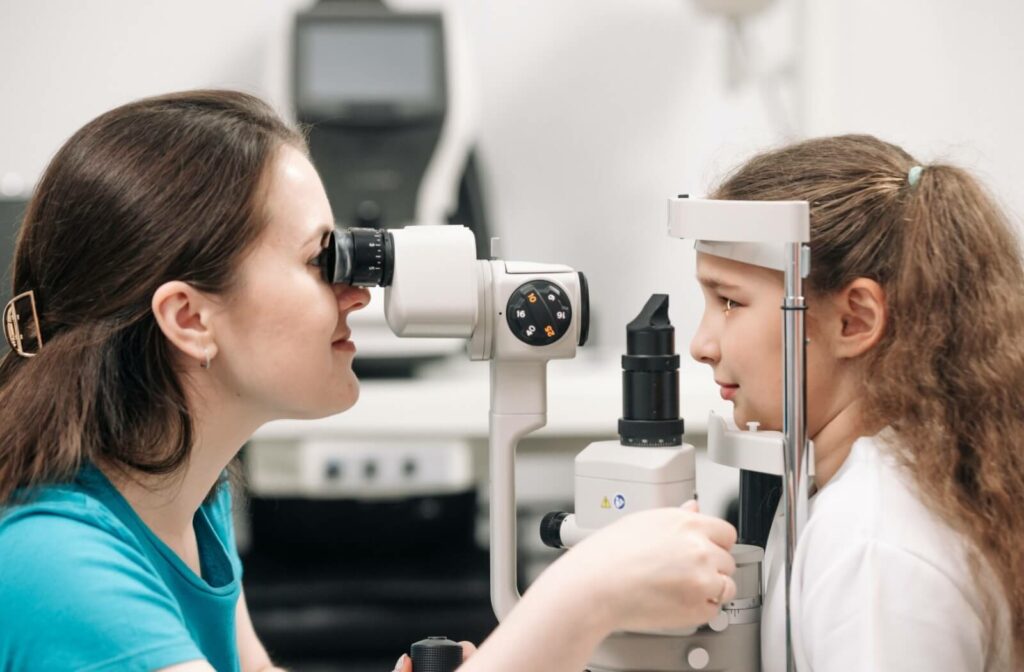 An optometrist examines a young child's retina with a slit lamp during a comprehensive eye exam.