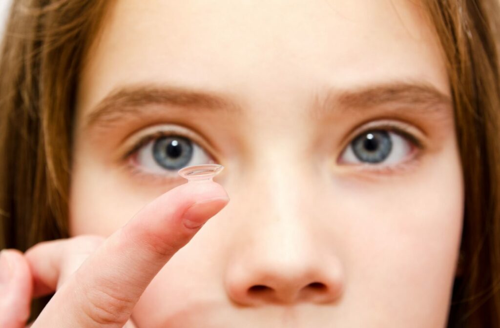 A child with myopia holds up a soft contact lens used to slow their myopia progression and correct their vision.
